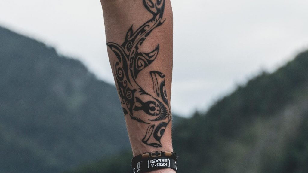 A tattoo design influenced by tribal art, typically featuring bold black lines and abstract patterns.